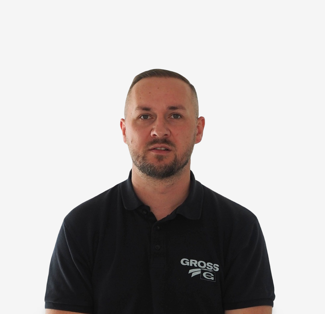 Ein Mann mit dunklem Polo-Shirt vor weißem Hintergrund, schaut direkt in die Kamera.