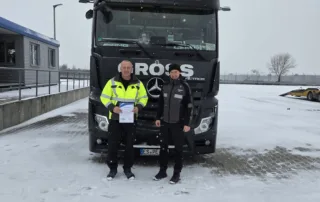 Zwei Personen stehen in Schneelandschaft vor einem großen Lkw mit der Aufschrift GROSS WIEDEMAR.
